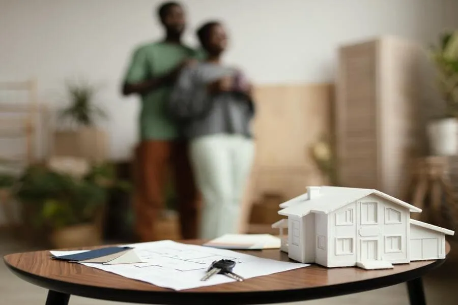 Blurred couple with a house model and keys on a table, from a tenant screening guide for tenants moving into a rental.