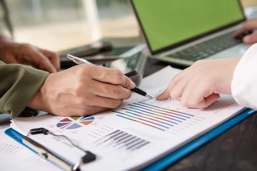 Two colleagues reviewing bar and pie chart reports, similar to comparing RS3 score vs credit score data.