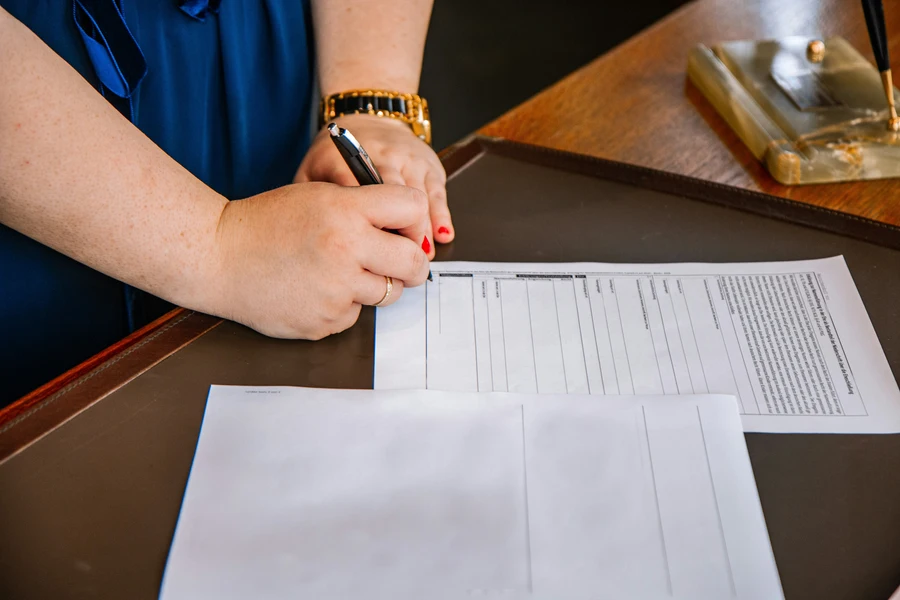 Renter signing lease agreement with pen showing move-in cost breakdown on documents