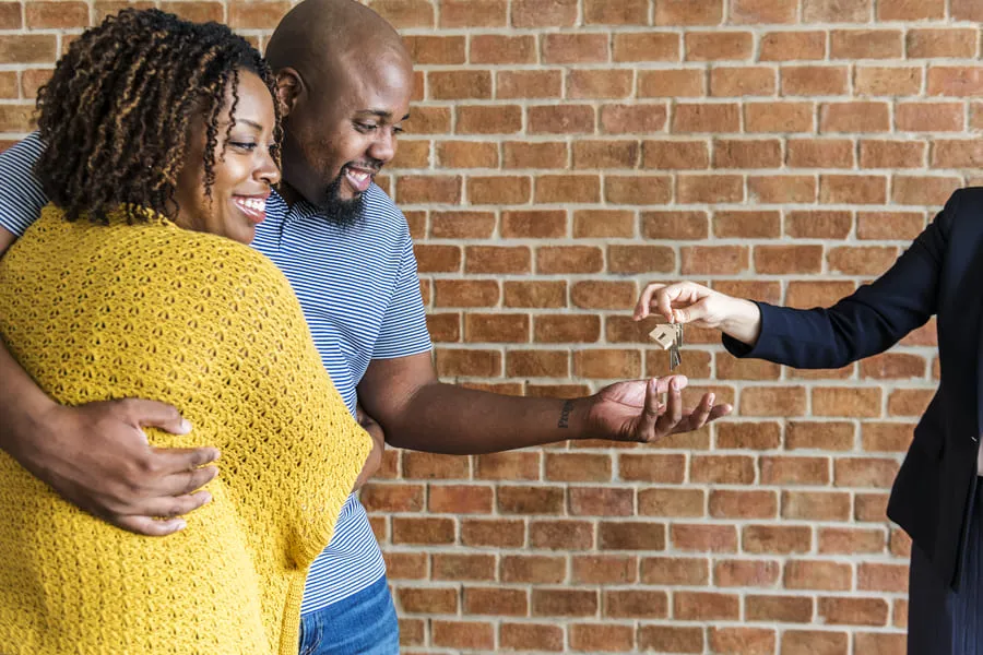 Couple receiving keys from a leasing agent after renting an apartment for the first time.
