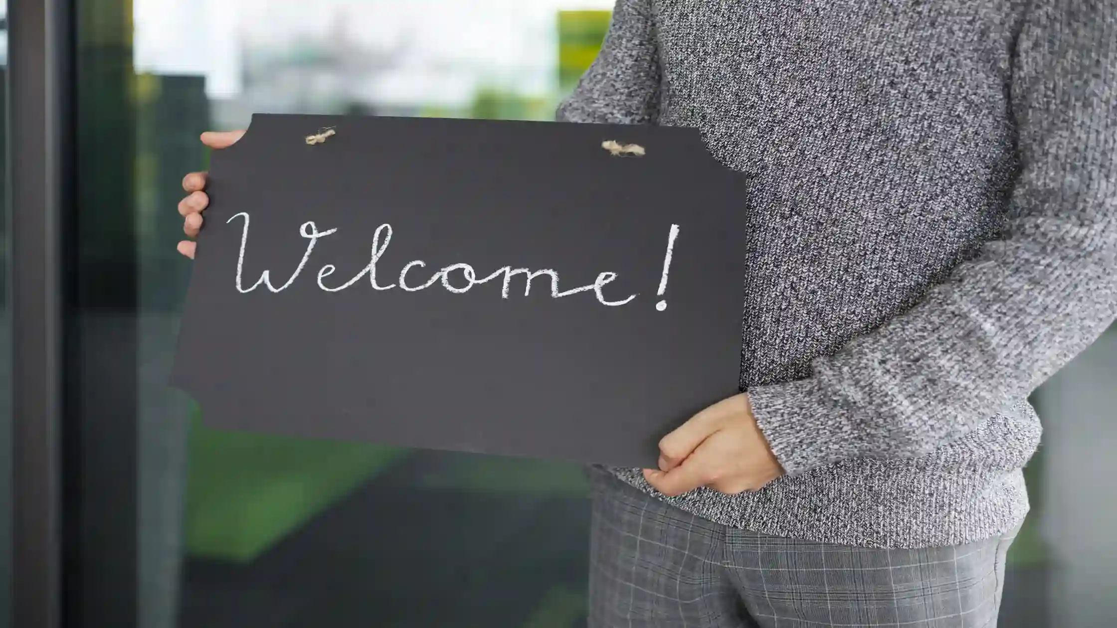 Landlord holding a Welcome sign to greet a new renter with a tenant welcome letter at move-in.