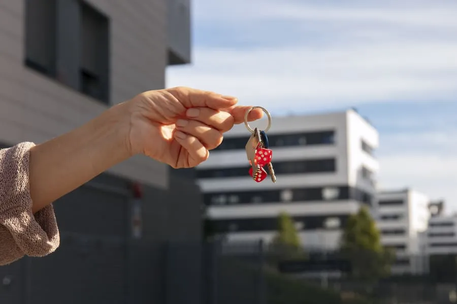 New tenant holding apartment keys outdoors, a common moment when renting an apartment for the first time.