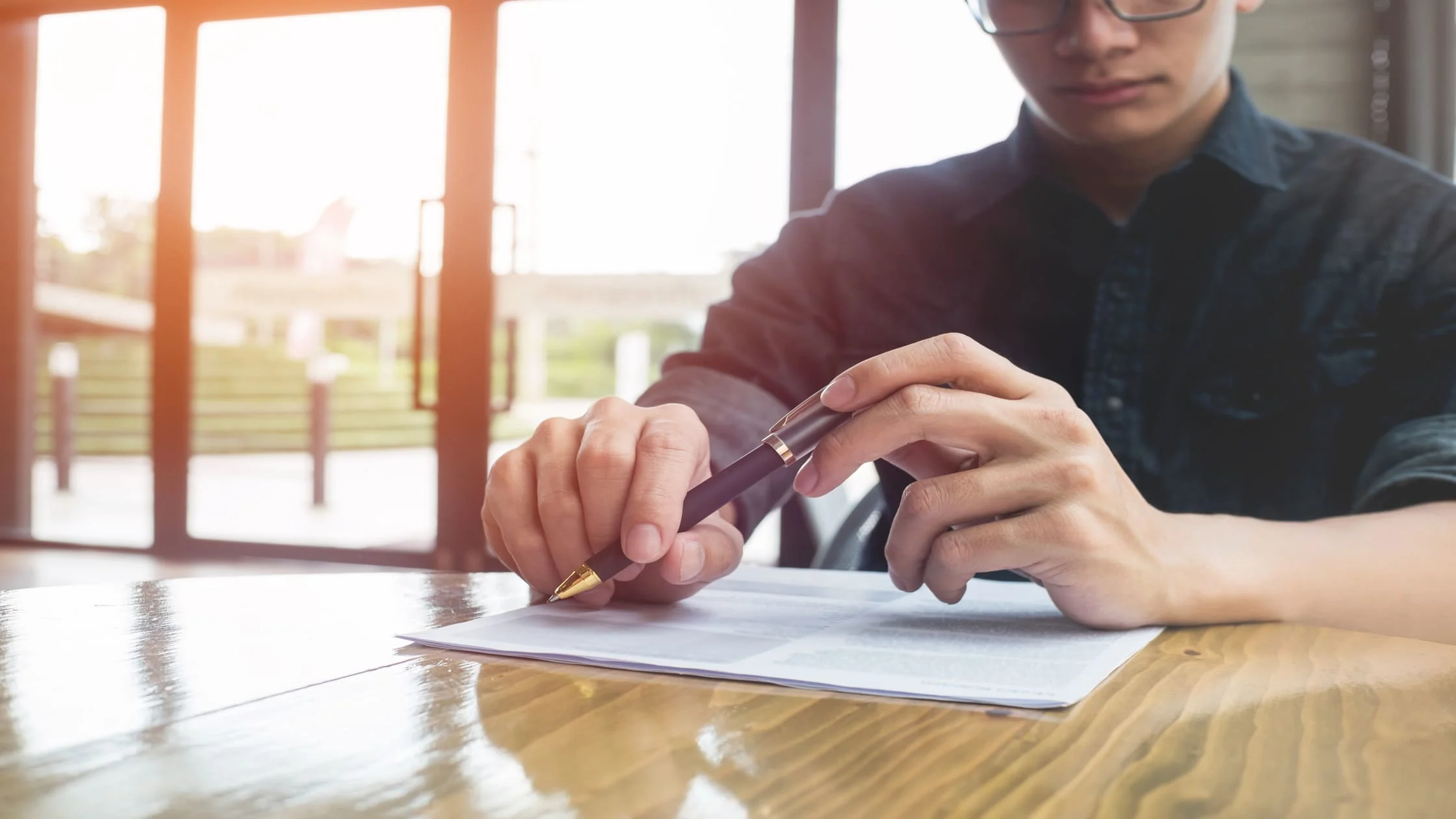 man-writing-on-lease-agreement-document-near-window-maintenance-clause